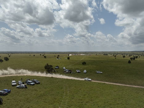 Aerial view of a rally car racing on a dirt track kicking up dust across the vast savanna of Swara Plains Conservancy with spectators and parked vehicles under a cloudy sky in Nairobi Machakos County Kenya. Aerial view of a rally car racing on a dirt track kicking up dust across the vast savanna of Swara Plains Conservancy with spectators and parked vehicles under a cloudy sky in Nairobi Machakos County Kenya.