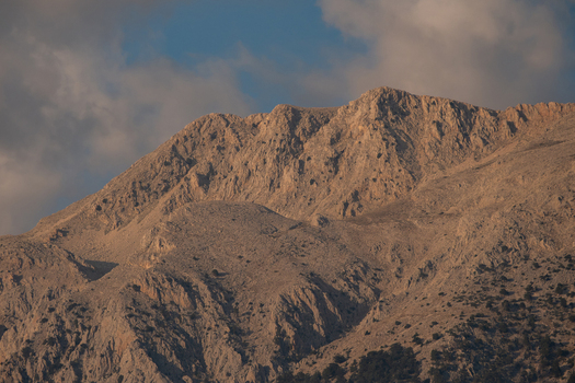 View of the rugged rocky slopes of a mountain peak illuminated by golden hour light under a soft sky in Fethiye Mugla Turkiye.