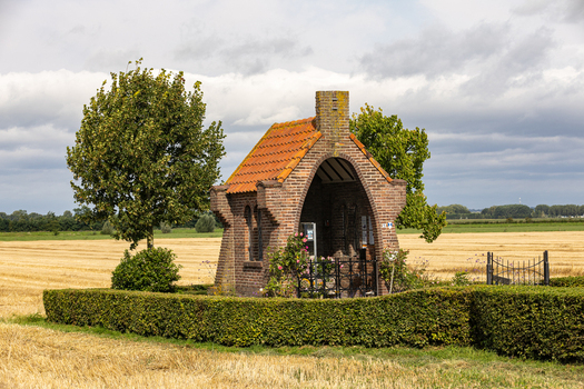 View of Kapel op De Heuvel a small brick chapel with an orange tiled roof surrounded by a green hedge in a harvested field Bemmel Gelderland Netherlands. View of Kapel op De Heuvel a small brick chapel with an orange tiled roof surrounded by a green hedge in a harvested field Bemmel Gelderland Netherlands.