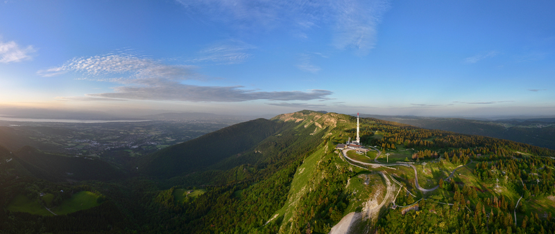 Aerial view of Col de la Faucille featuring a communication tower atop lush green mountain slopes dense forests and a panoramic view of the valley in Gex Auvergne Rhone Alpes France.