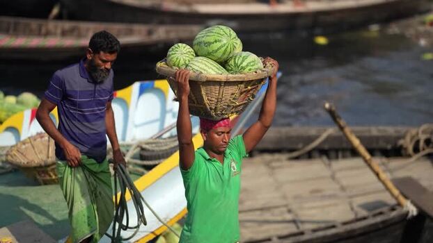 View of a worker carrying watermelons at Sadarghat Bangladesh.