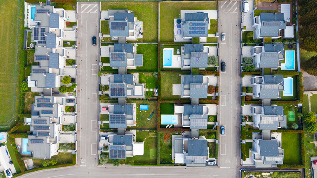 Aerial view of modern residential houses featuring private gardens swimming pools and rooftop solar panels in a suburban neighborhood in Milan Lombardy Italy.