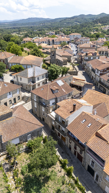 Aerial view of historic Allariz with traditional stone houses terracotta rooftops and a church tower surrounded by green hills in Allariz Province of Ourense Spain. Aerial view of historic Allariz with traditional stone houses terracotta rooftops and a church tower surrounded by green hills in Allariz Province of Ourense Spain.