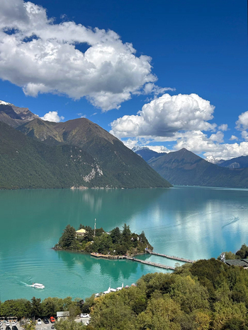 Aerial view of Batongtso Lake with its small island wooden walkways turquoise water and surrounding mountains under a blue sky Xizang China. Aerial view of Batongtso Lake with its small island wooden walkways turquoise water and surrounding mountains under a blue sky Xizang China.