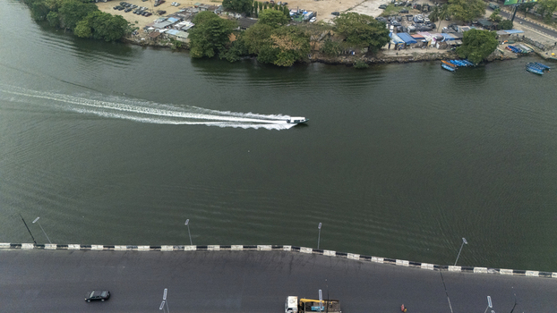 Aerial view of a motorboat speeding across the water near Lagos Island with a bridge and road visible in the foreground Lagos Lagos Nigeria. Aerial view of a motorboat speeding across the water near Lagos Island with a bridge and road visible in the foreground Lagos Lagos Nigeria.