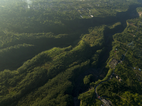 Aerial view of the Kali Gendol river valley surrounded by lush green forests and misty hills in Cangkringan Special Region of Yogyakarta Indonesia.