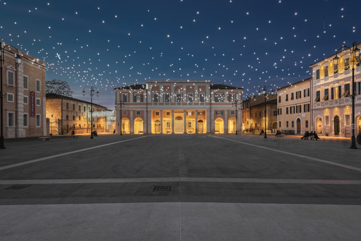 View of Piazza del Duca in Senigallia at night illuminated by festive string lights hanging above the historic square surrounded by elegant architecture in Senigallia Marche Italy.