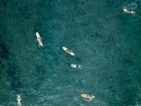 Aerial view of surfers on surfboards paddling in the clear turquoise waters at Mahaybo Beach General Luna Caraga Philippines. Aerial view of surfers on surfboards paddling in the clear turquoise waters at Mahaybo Beach General Luna Caraga Philippines.