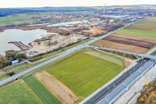 Aerial view of a gravel quarry and industrial site next to a lake surrounded by agricultural fields and railway tracks in Forchheim Bavaria Germany. Aerial view of a gravel quarry and industrial site next to a lake surrounded by agricultural fields and railway tracks in Forchheim Bavaria Germany.