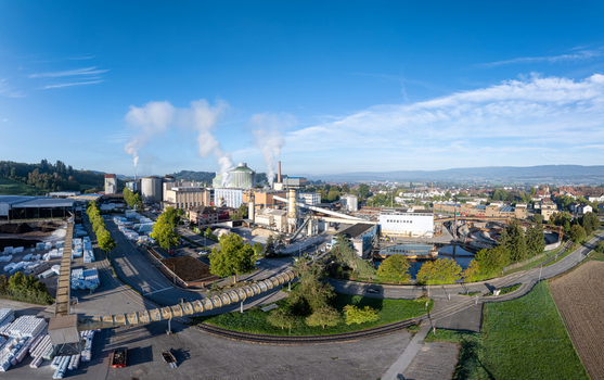 Aerial view of the Zuckerfabrik sugar factory with industrial buildings smoking chimneys and conveyor systems surrounded by green fields in Aarberg Bern Switzerland. Aerial view of the Zuckerfabrik sugar factory with industrial buildings smoking chimneys and conveyor systems surrounded by green fields in Aarberg Bern Switzerland.