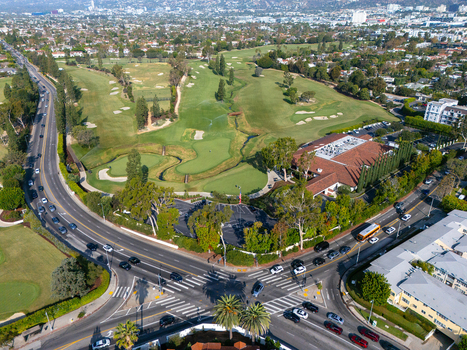 Aerial view of Wilshire Country Club featuring lush green fairways sand bunkers and the clubhouse surrounded by urban streets and palm trees in Los Angeles California United States. Aerial view of Wilshire Country Club featuring lush green fairways sand bunkers and the clubhouse surrounded by urban streets and palm trees in Los Angeles California United States.
