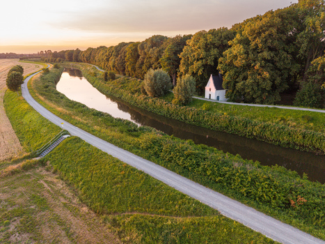 Aerial view of Kapel O L Vrouw in t Hammeke situated along the Zenne river surrounded by lush trees and rural fields during a golden sunset in Zemst Flanders Belgium. Aerial view of Kapel O L Vrouw in t Hammeke situated along the Zenne river surrounded by lush trees and rural fields during a golden sunset in Zemst Flanders Belgium.