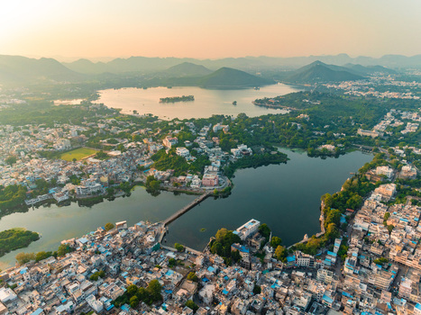 Aerial view of the historic city of Udaipur with its dense urban rooftops intricate architecture and serene lakes surrounded by lush hills in Udaipur Rajasthan India. Aerial view of the historic city of Udaipur with its dense urban rooftops intricate architecture and serene lakes surrounded by lush hills in Udaipur Rajasthan India.