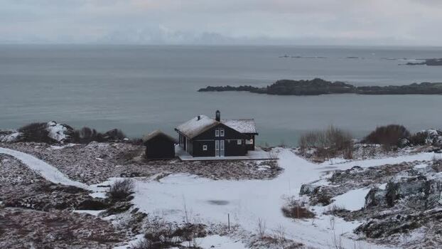Aerial view of a dark wooden house in Lofoten Norway.