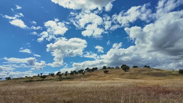 View of a dry field and a hill under a cloudy sky Portugal.