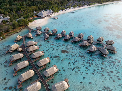 Aerial view of Sofitel Kia Ora Moorea Beach Resort featuring overwater bungalows extending into the turquoise lagoon with coral reefs in Moorea Maiao Windward Islands French Polynesia. Aerial view of Sofitel Kia Ora Moorea Beach Resort featuring overwater bungalows extending into the turquoise lagoon with coral reefs in Moorea Maiao Windward Islands French Polynesia.