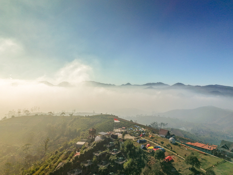 Aerial view of Sunrise Point Cukul with colorful camping tents nestled among lush tea plantations and rolling hills shrouded in morning mist in Kecamatan Pangalengan Jawa Barat Indonesia. Aerial view of Sunrise Point Cukul with colorful camping tents nestled among lush tea plantations and rolling hills shrouded in morning mist in Kecamatan Pangalengan Jawa Barat Indonesia.