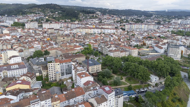 Aerial view of the dense urban landscape with historic terracotta rooftops modern apartment buildings and lush green parks in Ourense Province of Ourense Spain.
