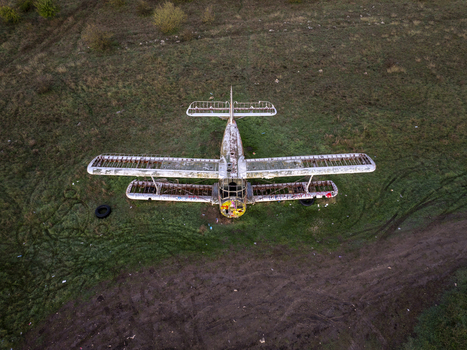 Aerial view of an abandoned biplane with skeletal wings and graffiti resting in a grassy field in Bulgaria. Aerial view of an abandoned biplane with skeletal wings and graffiti resting in a grassy field in Bulgaria.