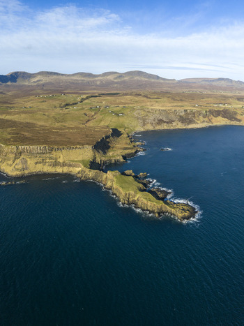 Aerial view of The Brother s Point peninsula jutting into the blue sea with steep cliffs and rolling green hills under a clear sky Culnacnoc Scotland United Kingdom. Aerial view of The Brother s Point peninsula jutting into the blue sea with steep cliffs and rolling green hills under a clear sky Culnacnoc Scotland United Kingdom.