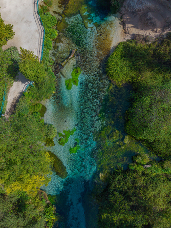 Aerial view of The Blue Eye with its vibrant turquoise spring water surrounded by lush green vegetation and trees in Saranda Qarku i Vlores Albania. Aerial view of The Blue Eye with its vibrant turquoise spring water surrounded by lush green vegetation and trees in Saranda Qarku i Vlores Albania.