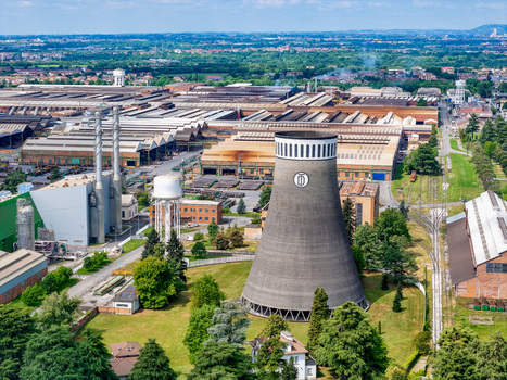 Aerial view of the TenarisDalmine industrial plant featuring its iconic cooling tower and large factory buildings under a clear blue sky in Dalmine Lombardy Italy. Aerial view of the TenarisDalmine industrial plant featuring its iconic cooling tower and large factory buildings under a clear blue sky in Dalmine Lombardy Italy.