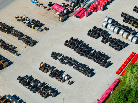 Aerial view of a warehouse yard filled with numerous rows of organized industrial cable reels and plastic pipes on a paved surface in Lielvarzi Kekava Municipality Latvia. Aerial view of a warehouse yard filled with numerous rows of organized industrial cable reels and plastic pipes on a paved surface in Lielvarzi Kekava Municipality Latvia.