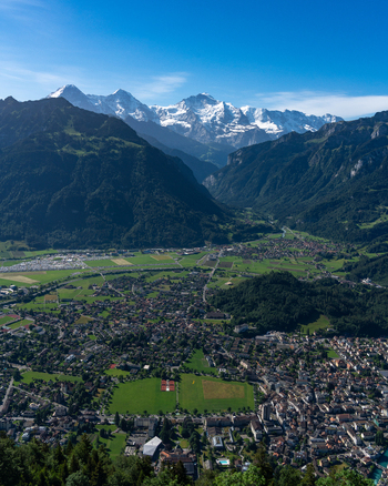 View of the town of Unterseen nestled in the valley below the snow capped peaks of the Bernese Alps as seen from Harder Kulm Unterseen Canton of Bern Switzerland.