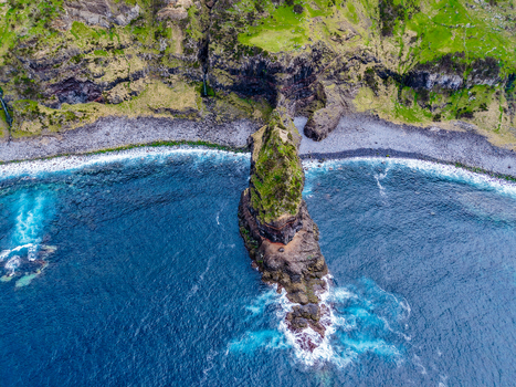 Aerial view of a rugged verdant islet rising sharply from the deep blue sea a stark contrast to the rocky shore and the lush cliffs Flores A&ccedil;ores Portugal.