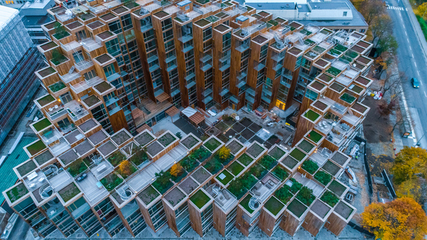 Aerial view of a modern wooden apartment complex featuring tiered terraces with green roofs and balconies in Sweden. Aerial view of a modern wooden apartment complex featuring tiered terraces with green roofs and balconies in Sweden.