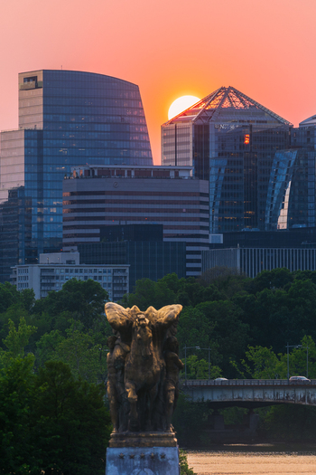 View of the Rosslyn skyline at sunset with modern skyscrapers and the Sacrifice statue in the foreground over the Potomac River in Arlington Virginia United States. View of the Rosslyn skyline at sunset with modern skyscrapers and the Sacrifice statue in the foreground over the Potomac River in Arlington Virginia United States.