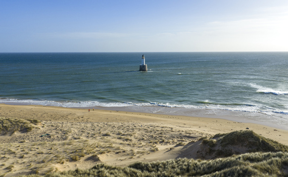 Aerial view of Rattray Head Lighthouse standing in the sea near a sandy beach with grassy dunes and people walking along the shore Peterhead Scotland United Kingdom. Aerial view of Rattray Head Lighthouse standing in the sea near a sandy beach with grassy dunes and people walking along the shore Peterhead Scotland United Kingdom.