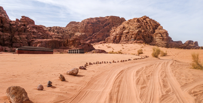 View of the vast Wadi Rum Desert landscape featuring towering sandstone rock formations traditional Bedouin tents and a sandy track in Wadi Rum Village Aqaba Governorate Jordan. View of the vast Wadi Rum Desert landscape featuring towering sandstone rock formations traditional Bedouin tents and a sandy track in Wadi Rum Village Aqaba Governorate Jordan.