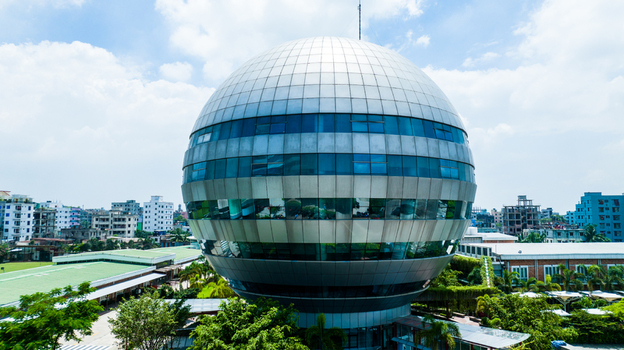 Aerial view of the spherical Bangabandhu Sheikh Mujibur Rahman Novo Theatre surrounded by lush greenery and urban buildings in Dhaka Dhaka Division Bangladesh. Aerial view of the spherical Bangabandhu Sheikh Mujibur Rahman Novo Theatre surrounded by lush greenery and urban buildings in Dhaka Dhaka Division Bangladesh.