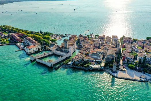 Aerial view of Castello Scaligero di Sirmione and the historic old town on the peninsula surrounded by the turquoise waters of Lake Garda in Sirmione Lombardia Italy.