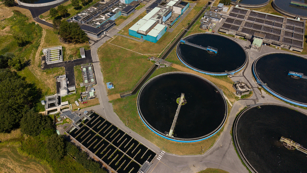 Aerial view of a wastewater treatment plant with large circular sedimentation tanks and rectangular basins surrounded by green space in Milan Lombardy Italy. Aerial view of a wastewater treatment plant with large circular sedimentation tanks and rectangular basins surrounded by green space in Milan Lombardy Italy.