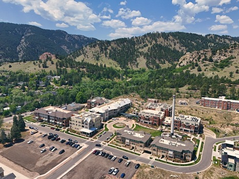 Aerial view of a residential development with a prominent chimney stack solar panels and parking lots nestled against the foothills in Boulder Colorado United States. Aerial view of a residential development with a prominent chimney stack solar panels and parking lots nestled against the foothills in Boulder Colorado United States.