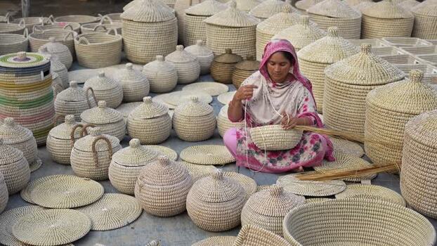 View of a woman weaving traditional baskets in Bogura Bangladesh. View of a woman weaving traditional baskets in Bogura Bangladesh.