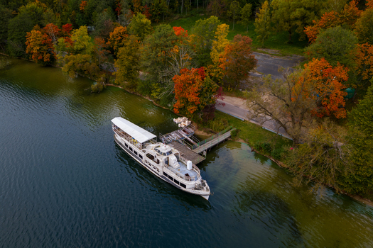 Aerial view of a large white passenger boat docked at a wooden pier on the calm waters of a lake surrounded by vibrant autumn foliage Trakai Vilnius County Lithuania. Aerial view of a large white passenger boat docked at a wooden pier on the calm waters of a lake surrounded by vibrant autumn foliage Trakai Vilnius County Lithuania.