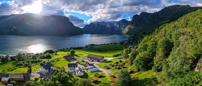 Aerial view of the village of Flam nestled between lush green mountains and the deep blue waters of the Aurlandsfjord in Vestland Norway. Aerial view of the village of Flam nestled between lush green mountains and the deep blue waters of the Aurlandsfjord in Vestland Norway.