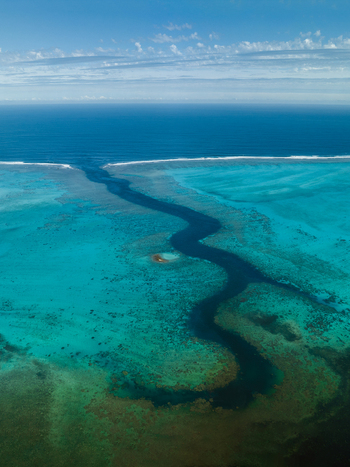 Aerial view of a vibrant turquoise channel carving through the reef where the deep blue sea meets the shallows Noumea South Province New Caledonia.