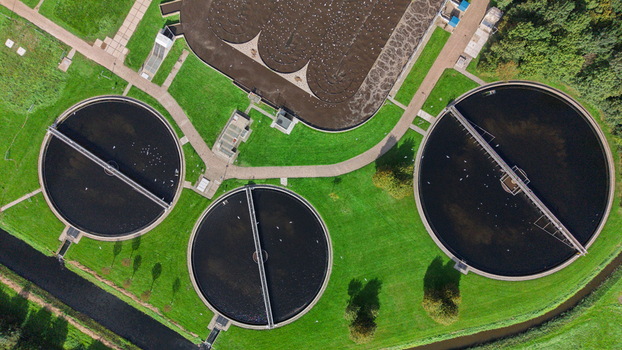 Aerial view of circular wastewater treatment tanks and infrastructure surrounded by green grass in Warmenhuizen North Holland Netherlands. Aerial view of circular wastewater treatment tanks and infrastructure surrounded by green grass in Warmenhuizen North Holland Netherlands.