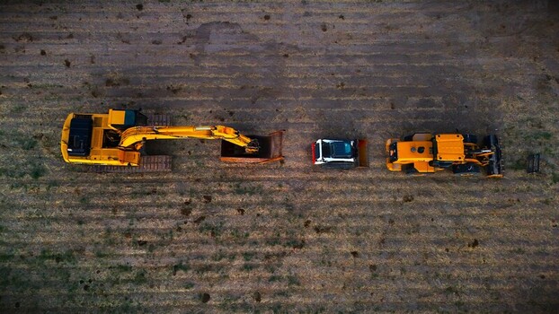 Aerial view of heavy machinery including an excavator a dump truck and a bulldozer standing in a field of dry grass Fruita Colorado United States. Aerial view of heavy machinery including an excavator a dump truck and a bulldozer standing in a field of dry grass Fruita Colorado United States.