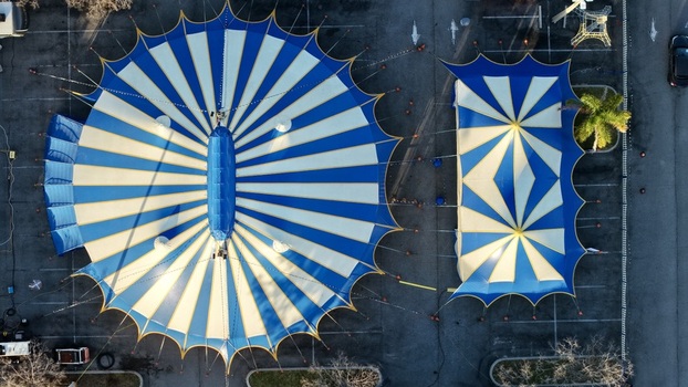 Aerial view of a vibrant blue and white striped circus tent and smaller tent casting long shadows on the asphalt St. Augustine Florida United States. Aerial view of a vibrant blue and white striped circus tent and smaller tent casting long shadows on the asphalt St. Augustine Florida United States.