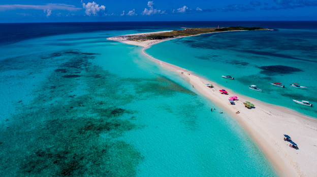 Aerial view of Los Roques archipelago with turquoise waters white sandbars and small boats anchored along the shore under a clear blue sky. Los Roques Dependencias Federale Venezuela. Aerial view of Los Roques archipelago with turquoise waters white sandbars and small boats anchored along the shore under a clear blue sky. Los Roques Dependencias Federale Venezuela.