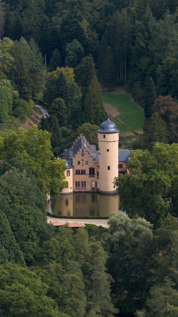 Aerial view of Schloss Mespelbrunn a historic water castle surrounded by dense forest and lush greenery in Mespelbrunn Bayern Germany. Aerial view of Schloss Mespelbrunn a historic water castle surrounded by dense forest and lush greenery in Mespelbrunn Bayern Germany.