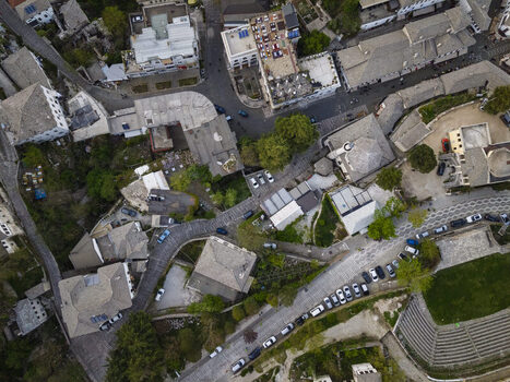 Aerial view of historic stone architecture and narrow streets in Gjirokaster featuring slate roofed houses and parked cars in Gjirokaster Gjirokaster County Albania. Aerial view of historic stone architecture and narrow streets in Gjirokaster featuring slate roofed houses and parked cars in Gjirokaster Gjirokaster County Albania.