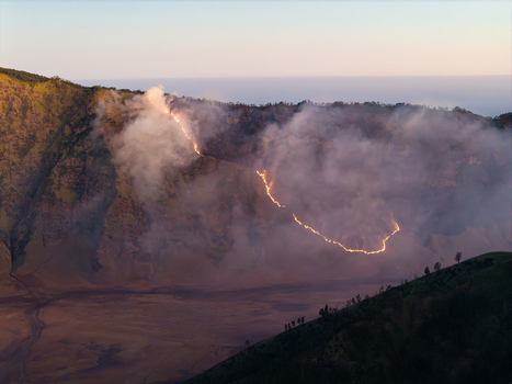 Aerial view of a wildfire burning along the ridge of Mount Bromo in Mount Bromo National Park with thick smoke rising over the volcanic landscape in Tosari East Java Indonesia.