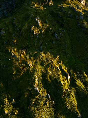 Aerial view of the rugged green slopes and rocky terrain of Tangstad during golden hour light Leknes Nordland Norway. Aerial view of the rugged green slopes and rocky terrain of Tangstad during golden hour light Leknes Nordland Norway.