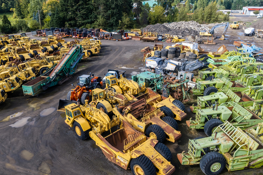 Woodburn Oregon United States 25 September 2026 Aerial view of a large construction equipment yard filled with yellow and green heavy machinery scrapers and loaders parked on a dirt lot. Woodburn Oregon United States 25 September 2026 Aerial view of a large construction equipment yard filled with yellow and green heavy machinery scrapers and loaders parked on a dirt lot.